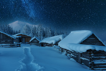 Wall Mural - Fairytale landscapes of the winter Carpathian Mountains with a charming milky way in the sky tourist tents and snowy houses in the valleys
