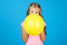 Pretty Little Girl Blowing Yellow Balloon On Blue Background
