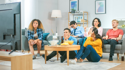 Wall Mural - In the Living Room Diverse Group of Friends on Watching Sports Game Match on TV, They Cheer and Chant for the Team, But are Disappointed after Team Loses. Cozy Room with Snacks and Drinks