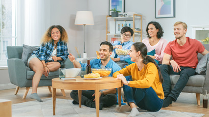 Wall Mural - At Home Diverse Group Friends Watching TV Together, Eating Snacks and Drinking Beverage. They Probably Watching Sports Game or Movie. Young People Having Fun Together.