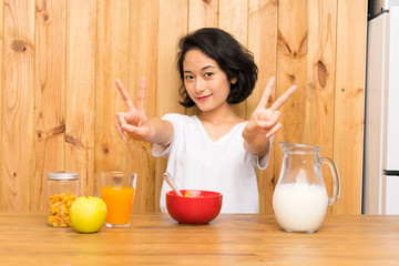 Asian young woman having breakfast milk smiling and showing victory sign