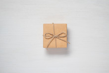 A Paper Gift Box Tied With Twine On A White Wooden Background. Gift Card Concept.