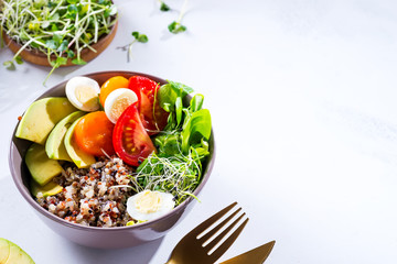 Fresh healthy salad with quinoa, cherry tomatoes and mixed greens, avocado, egg and micro greens on marble background top view. Food and health. Superfood meal. Clean eating. Healthy lifestyle