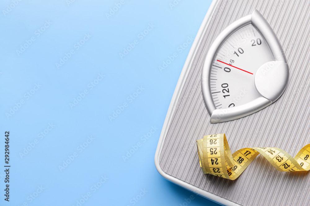 Scales and measuring tape on color background. Weight loss concept