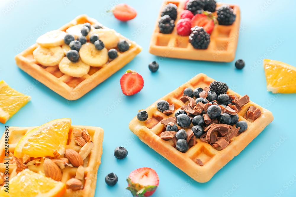 Tasty waffles with fruits and berries on color background