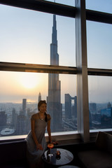 Wall Mural - Woman enjoying a drink with downtown Dubai view