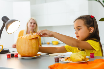 Wall Mural - Cute little child girl with carving pumpkin.