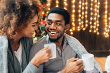 Young Couple Drinking Coffee At Christmas Tree