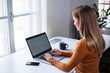 © eshana_blue - Young millennial working on laptop standing at the desk by the window