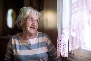 Wall Mural - Elderly woman sits near the window.