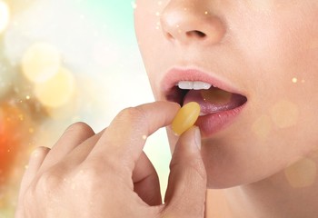 Canvas Print - Woman taking a tablet. Close up hand with a pill and the mouth, isolated on background