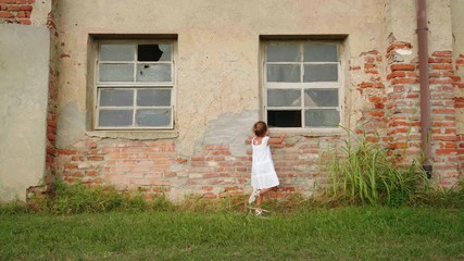 Wall Mural - Authentic shot of curious little girl is having fun to explore an old abandoned countryside building on a sunny day.