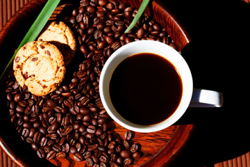 closeup top view white coffee cup roasted beans and cookies on wooden plank relaxing in day light