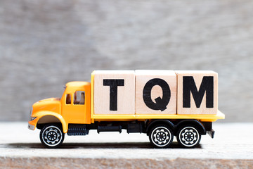 Poster - Truck hold letter block in word TQM (Abbreviation of total quality management) on wood background