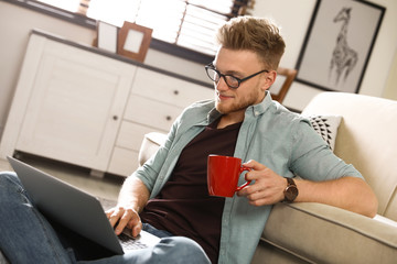 Wall Mural - Young man using laptop in living room