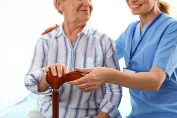 Canvas Print - Nurse in uniform assisting elderly woman indoors, closeup