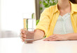 © New Africa - Woman holding glass of water at white table, closeup. Refreshing drink