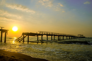 Sunset broken bridge on beach with sky