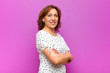 © kues1 - middle age woman smiling to camera with crossed arms and a happy, confident, satisfied expression, lateral view against purple wall