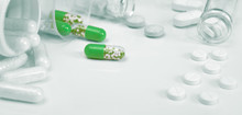Closeup On Bright Green Capsules And White Pills On White Background