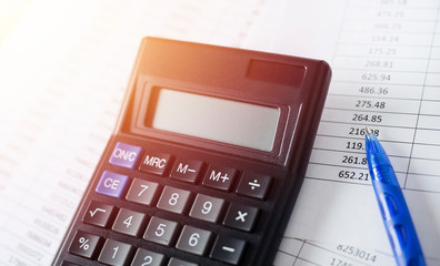 Calculator with pen on white paper with numbers. Business and Finance accounting concept.