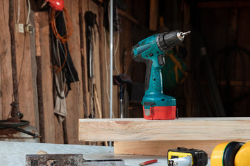 A man carpenter twists a screw into a tree with an electric screwdriver, male hands with a screwdriver close-up. Work with wood.