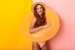 Photo of redhead pretty woman wearing straw hat and swimsuit standing in swim ring and smiling