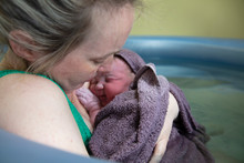 A New Mother Embracing Her Newborn Baby After A Natural Pool Home Birth