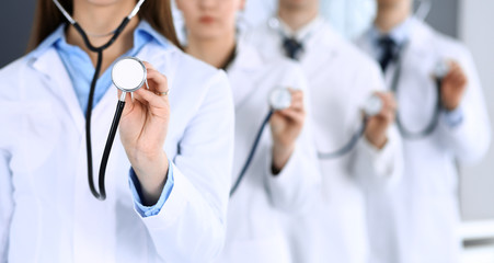 Wall Mural - Group of doctors holding stethoscope head close-up. Physicians ready to examine and help patient. Medical help, insurance in health care, best treatment and medicine concept