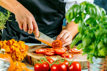 Wall Mural - Koch schneidet frische rote Tomaten in Restaurant küche 