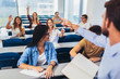 © Mediteraneo - Group of students raising hands in class on lecture