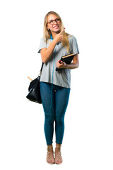 Poster - A full-length shot of Student girl with glasses pointing to the side with a finger to present a product or an idea while looking forward smiling on isolated white background