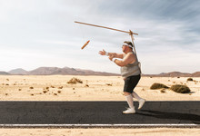 Funny Overweight Man Chasing The Hot Dog On The Stick Through The Empty Road With Copy Space
