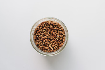 Wall Mural - Raw buckwheat in glass on white background, heathy food, diet