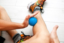 The Man Is Massaging His Leg By Massage Ball At Home