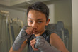 Asian American teenager boxing on gym . Portrait of young handsome and fierce 13 or 14 years old boy in wrist wraps doing fight workout looking cool in tough attitude