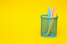 Blue Pencil Basket Holder With Colored Pens On Vivid Yellow Background With Negative Space.
