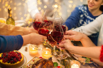 Canvas Print - holidays and celebration concept - close up of happy friends having christmas dinner at home, drinking red wine and clinking glasses