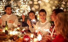 Winter Holidays And People Concept - Happy Friends With Sparklers Celebrating Christmas At Home Feast