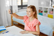 © Syda Productions - people, children and technology concept - girl with smartphone taking selfie at home