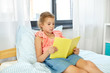 © Syda Productions - people, childhood and leisure concept - happy little girl reading book at home