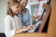 © goodluz - Little girl taking piano lesson, teacher watching her