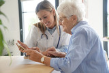 Fototapeta  - Elderly woman with nurse at home looking at tablet