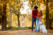 Multiracial couple walking with dog in autumn park
