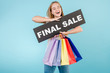 © Anastasia - happy smiling blonde woman with final sale sign and colorful shopping bags isolated over blue