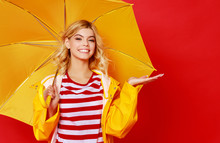 Young Happy Emotional Cheerful Girl Laughing And Jumping With Yellow Umbrella   On Colored Red Background.