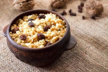 Wall Mural - Sweet millet porridge with dark raisins in ceramic rustic bowl