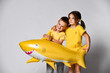 © FAB.1 - children in yellow clothes, wears a balloon in the shape of a yellow shark fish, celebrates a holiday, has a wide smile, stands on a light background, being in a good mood