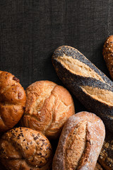 Wall Mural - Mixed baguettes and bread rolls on dark grey wood. Top view. Space for text.