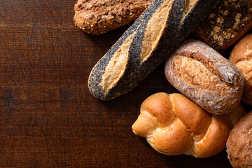 Wall Mural - Mixed baguettes and bread rolls on rustic dark wood. Top view. Space for text.